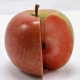 A single red love apple showing the brigh red to pink flesh which is quite unusual