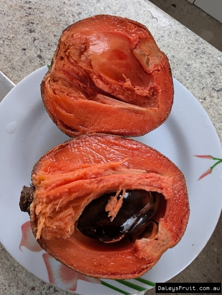 Grey Mamey Sapote cut to show orange flesh and brown seed