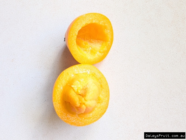 Halved sweet yellow mangosteen showing seed segments inside soft fruit.